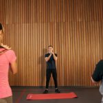Fitness instructor leading a training session with two women in a modern gym setting.